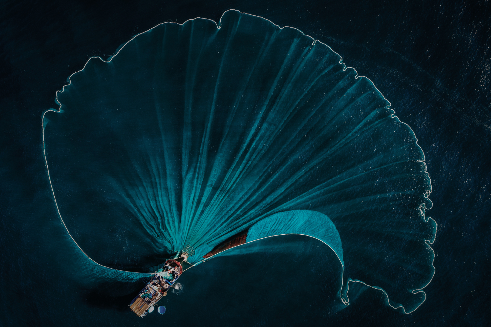 An aerial view of a Philippine fishing net opening across the sea